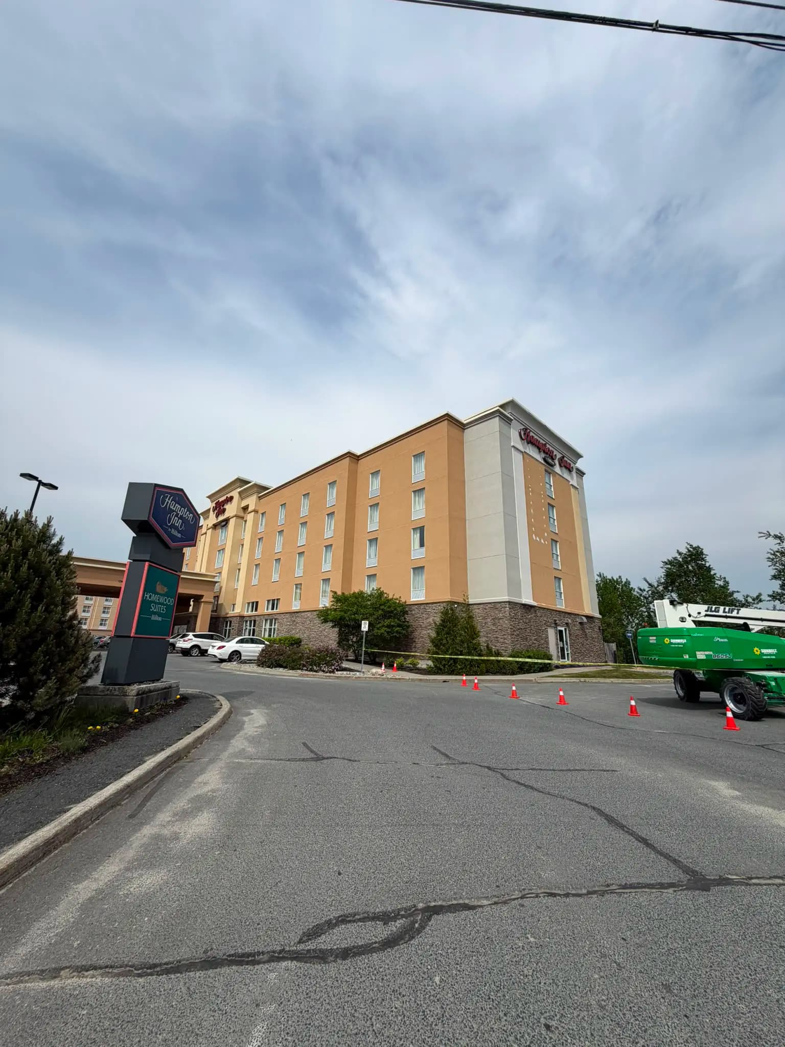 Hampton Inn, Greater Sudbury — Lift on site and the work zone taped off, with the building still beige