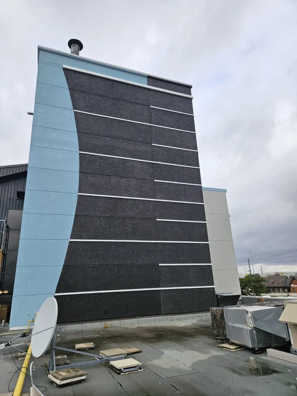 Holiday Inn, Burlington — The finished tower: charcoal panel field, white reveals, blue curve