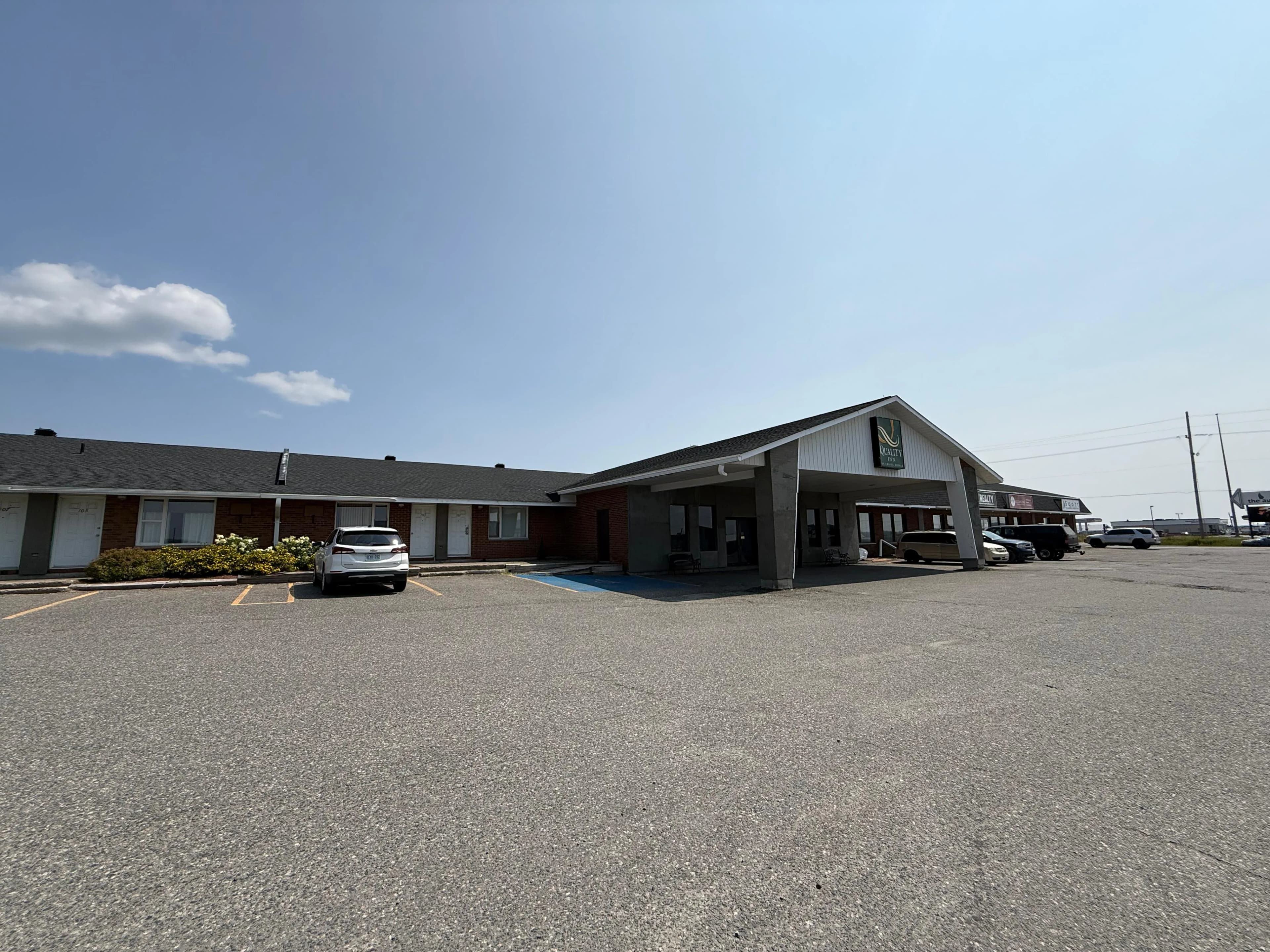Quality Inn, New Liskeard — Before: original red brick and dark trim on the entrance approach